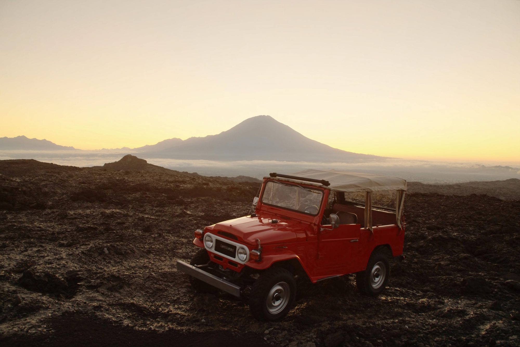 A classic 4x4 jeep on the black lava field of Mount Batur at dawn