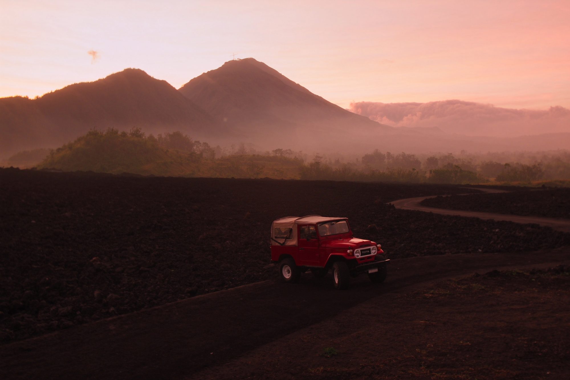 A classic 4x4 jeep on the lava road of Mount Batur at dusk