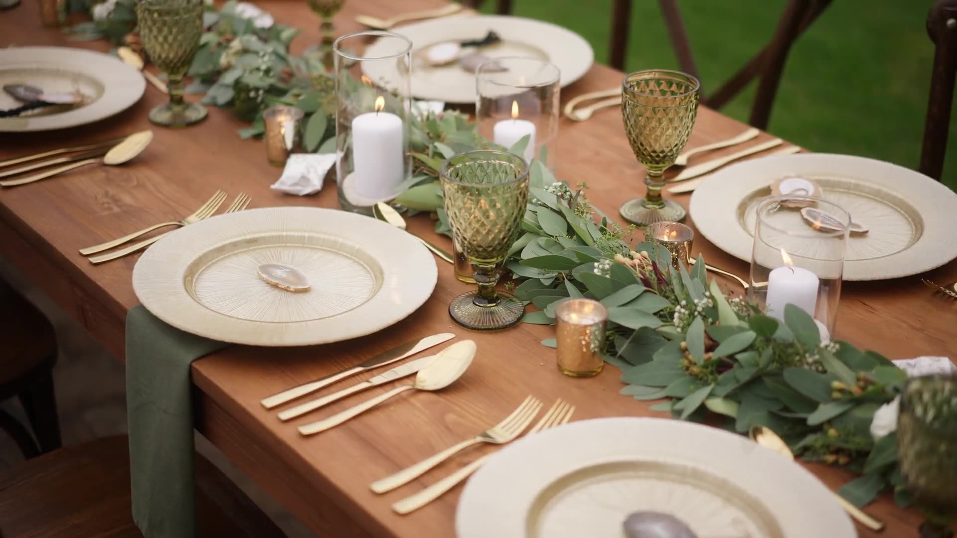 A candlelit table set with wine cups and plants