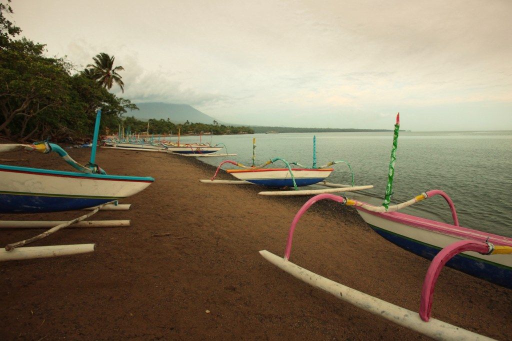 Painted fishing boats on the black sand at Amed