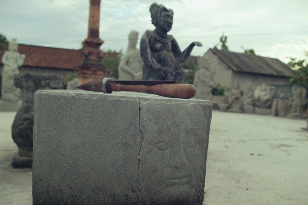 A stone temple guardian being carved in Batubulan